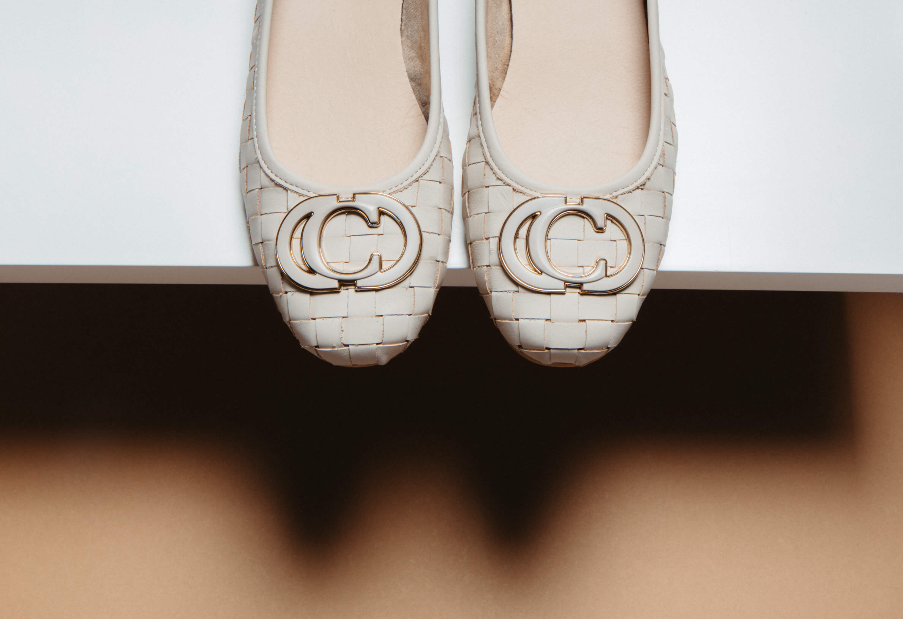 Weißer Leder-Ballerina mit geflochtenem Muster und goldener Zierspange